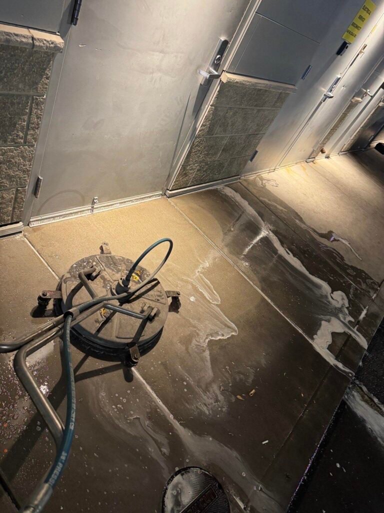 Surface cleaner working a back-of-house service area with detergent lifting grease from the concrete