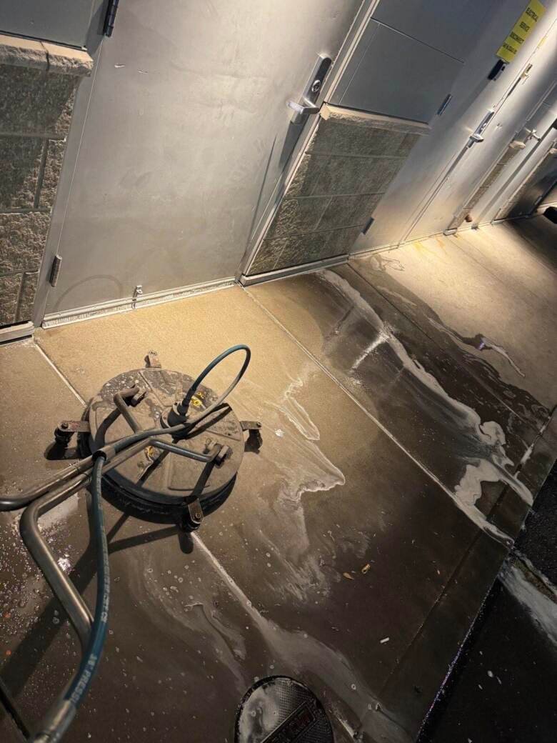 Surface cleaner working a back-of-house service area with detergent lifting grease from the concrete
