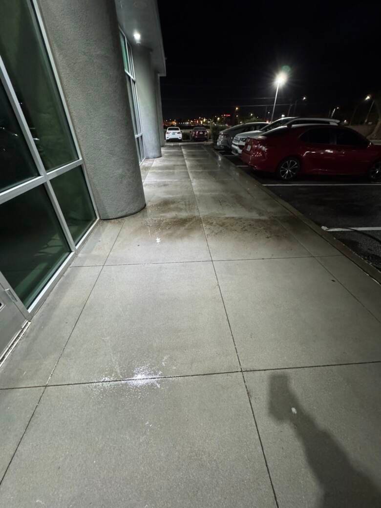 Cleaned commercial walkway beside parked cars in a lot at night
