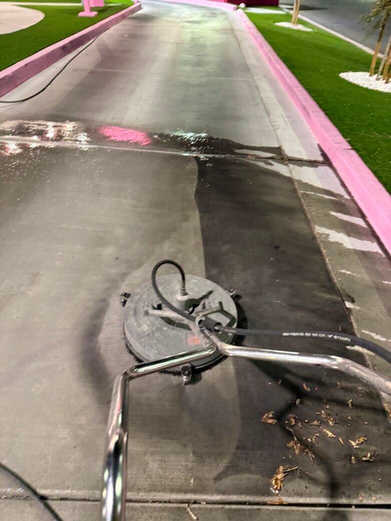 Drive-thru lane being washed at night, showing cleaned concrete beside heavily soiled concrete