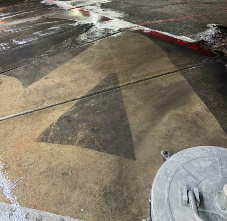 Painted directional arrow on drive-thru concrete being cleaned at night