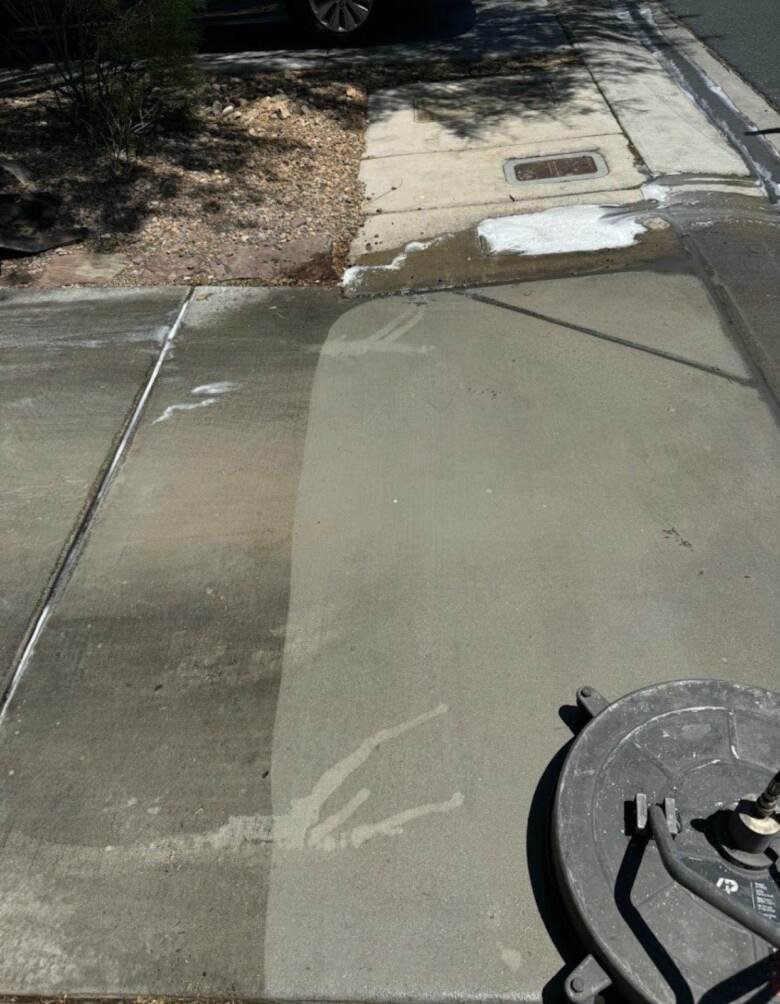 Driveway being cleaned, with a clear line between the washed strip and the dirty concrete beside it