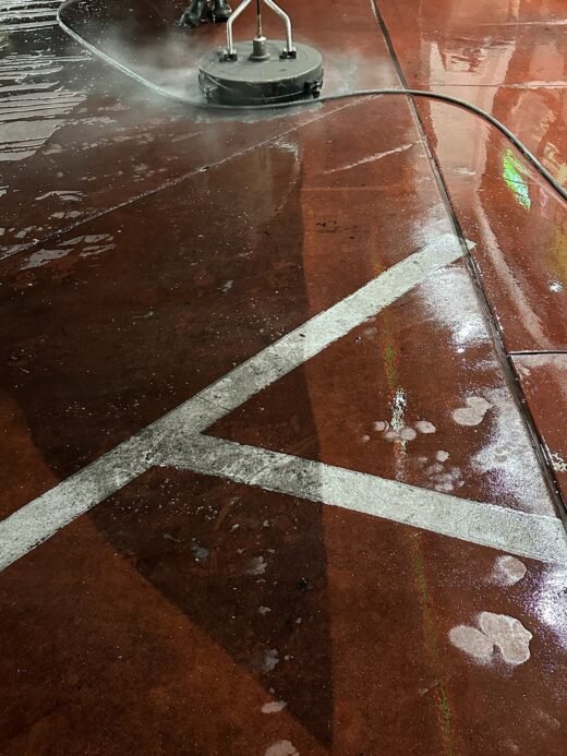 Hot water surface cleaner cleaning painted fuel pad concrete at a Las Vegas gas station at night