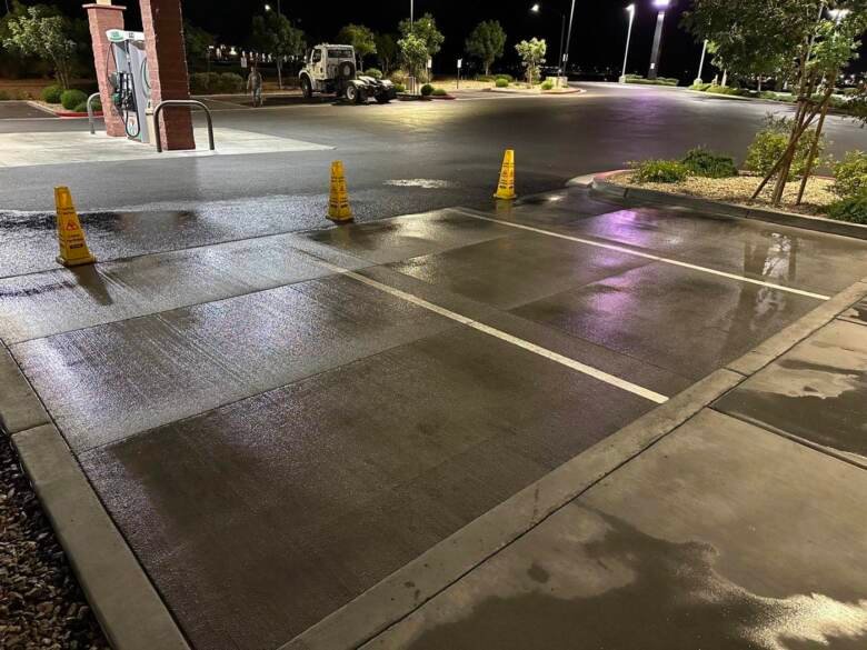 Cleaned commercial parking area at night with wet floor cones and painted stall lines