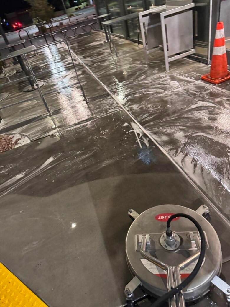 Restaurant exterior seating area being cleaned at night with a safety cone in place