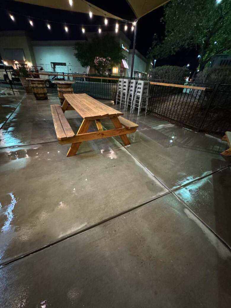 Restaurant patio at night with picnic tables on freshly cleaned concrete under string lights