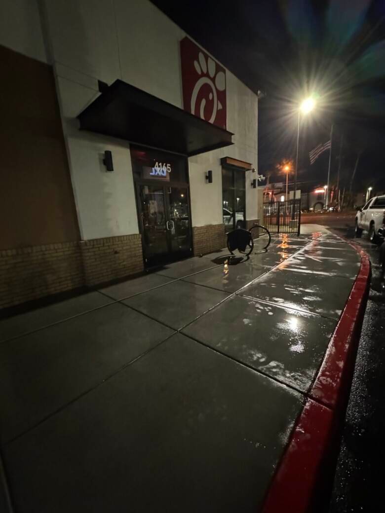 Clean sidewalk and red curb outside a lit restaurant storefront at night