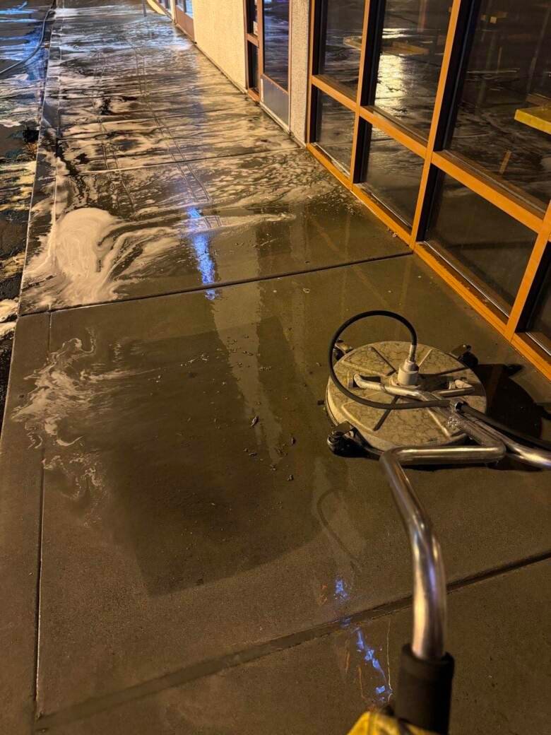 Surface cleaner washing a lit storefront walkway at night