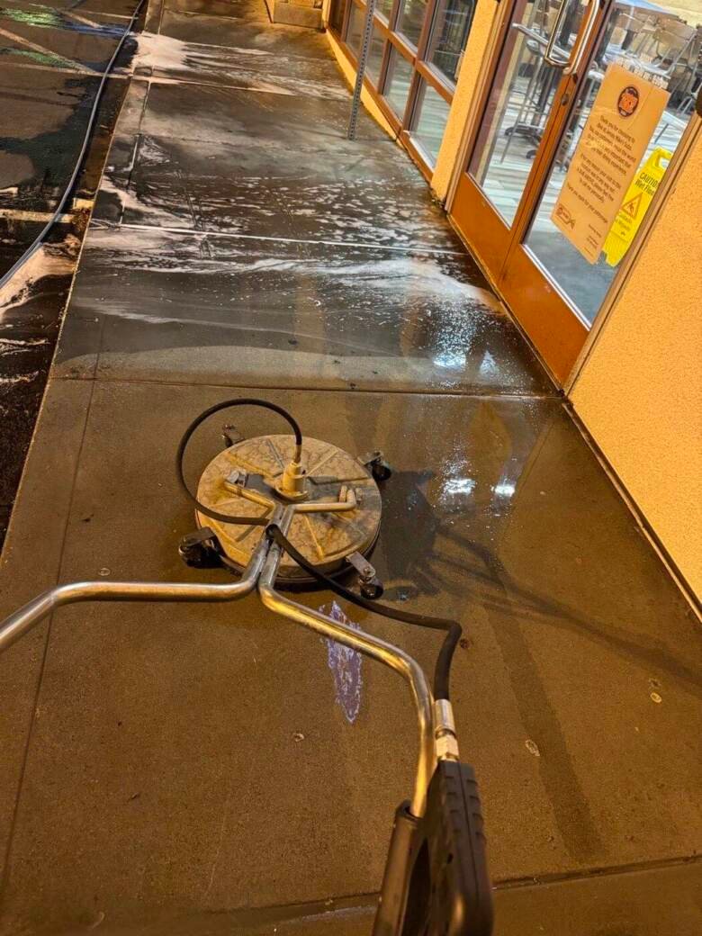 Surface cleaner working along a retail storefront walkway at night