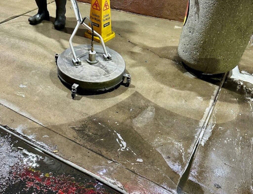 Surface cleaner on commercial concrete beside a wet floor caution sign